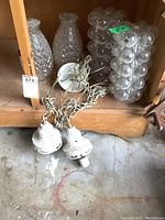 Wide view of four glass light fixtures and two white metal light fixtures with cords on floor of wooden cabinet.