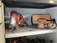 Shelf with Craftsman laser jigsaw and Ridgid palm sander with carrying case