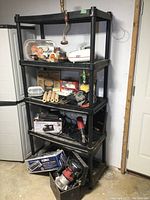 Front angle view of the black resin shelf loaded with various items showing condition and size.