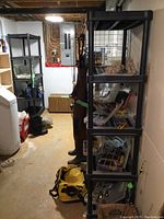 Full view of both black resin shelving units with grid back panels in basement setting, showing structural details and size relative to other items in the room.