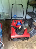 Front angle view of red snowblower in storage shed