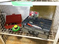 Overview of gray and red tackle boxes on a shelf, showing their size and some contents including baits and fishing lure containers.