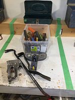 Two pry bars, small hand plane, and stapler placed in front of plastic bin and toolbox