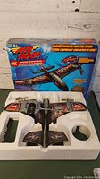 Photo of Air Hogs Resistor RC airplane and controller in original styrofoam packaging with box behind.