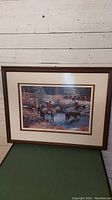 Framed limited edition print titled 'Crossing the Creek', showing a rural scene with riders and cattle crossing a creek. Print signed and numbered, with visible natural color scheme.