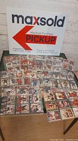 Photo showing multiple hockey cards spread out on a table in protective sleeves with a MaxSold pickup sign in the background.