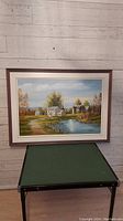 Framed oil painting of a homestead scene with white house, barn, trees, and pond against a light blue sky