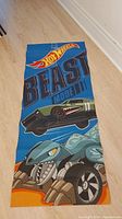 Blue Hot Wheels Beast Mode exercise mat laid on floor showing full design including car and shark face graphics.