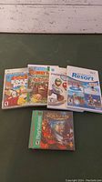 Photo showing six video game cases from Nintendo Wii and Sony PlayStation. Covers include The Simpsons Road Rage, Donkey Kong Country Returns, Super Mario Galaxy 2, and Wii Sports Resort among Wii titles, plus Legend of Dragoon for PlayStation.