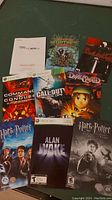 Photo showing 9 video game manuals for Nintendo DS, Xbox 360, and PC games arranged on a floor.