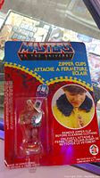 Sealed original packaging showing the Masters of the Universe branded zipper clip featuring He-Man figure, with branded cardboard display and usage photo.