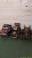 Front view of three vintage RC trucks: Batmobile-style truck, 4x4 racing truck, and rally truck