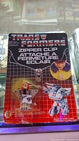 Front view of the vintage Transformers zipper clip in original packaging, showing the toy and branding.