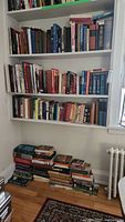 Books on three shelves and floor showing a large collection of assorted novels and history books