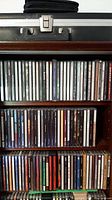 Three shelves of assorted music CDs showing various artists and genres.