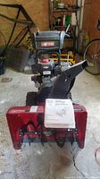 Front view of snowblower and printed owner’s manual placed on housing