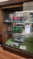 Three models displayed on glass shelving: red MG TC, green Morgan 3-Wheeler, silver Porsche 550 Spyder