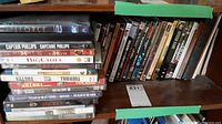 Full view of DVDs stacked on shelf showing multiple identifiable movie titles.