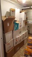 Stack of over 20 cardboard boxes packed with empty bottles in basement corner