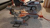 Angled side view showing entire saw on carpet with sliding rails and base plate