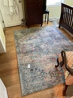 Full view of the large blue toned area rug on a wooden floor beneath furniture.
