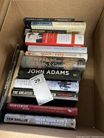 Box of books showing titles on spines relating to history, crime, politics, memoirs, and cookbook
