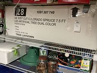 Box labeling with detailed product information including model number, size, color options, and features of the GE artificial Christmas tree.