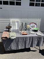 Wide shot of all items on a grey tablecloth including tablecloths, utensil trays, cake stand, platter, bowl, and dessert plates