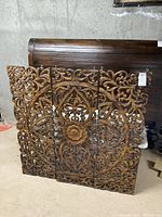 Front view of one wooden wall carving panel showing intricate floral and geometric design with a large central flower.