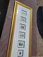 Full image of the six small AJ Casson prints vertically arranged in one gold frame against a brown carpet background, showing the set size and frame condition including a dent