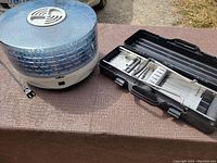 Photo showing the Salton food dehydrator and mandolin slicer in black case on a table outdoors