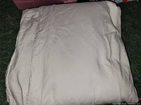 Folded light gray fabric duvet cover photographed on a dark surface to show color and texture.