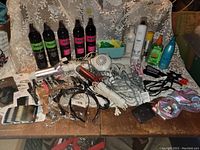 Multiple Revlon hair care spray bottles, white and silver hair dryers, curling irons in white and red, various hair combs and clips, black satin scrunchies and a large decorative comb.