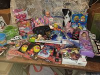 Full view of all items in the lot on the table showing variety of toys, dolls, games, and accessories
