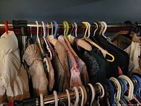 Clothing items hanging on two-level garment rack showing sweaters, knitwear, and tops in neutral and pastel shades.