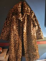 Front view of large ladies leopard print jacket with long sleeves and body length below hips, hanging on a wall.
