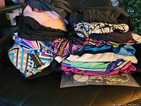 Pile of assorted women's swimsuits tops in various colors and patterns including geometric and floral designs.