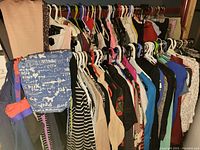 Wide view showing a large variety of ladies medium clothing items on hangers including tops, jackets, and dresses in various colors.