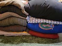 Stack of men’s clothing including sweaters, shirts, and a jacket showing colors and variety.