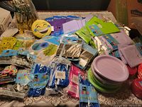 Lot of assorted brand new party supplies including napkins, plates, straws, and party favor items on a table.