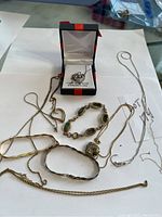 Photo showing all jewelry pieces arranged on white paper, including chains, bracelets, and a boxed heart pendant