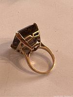 Ring displayed on white surface showing side view of gemstone and band