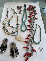 Full view of all 3 necklaces, anklet, pin and earrings arranged on white background