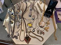 Full view of jewelry lot including necklaces, rings, and pendants on mirrored surface