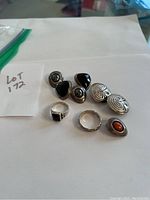 Photo showing all earrings and rings of the lot arranged on a white paper with lot number note