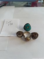 All 4 rings shown together including a turquoise ring, coin buffalo ring, round stone ring and engraved design ring.