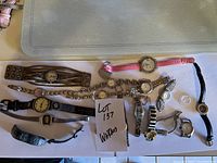Ten watches and watch bands laid out on table showing styles and condition