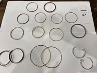 Top-down photo of assortment of hoop earrings and bangle bracelets arranged on white surface with a lot number card.