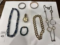 Full view of blue and white beaded necklace, two bracelets, watch, chunky gold-tone chain necklace, and silver-tone linked necklace