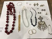Full view of the jewelry assortment laid flat on a surface showing all necklaces, earrings, pins, and rings.